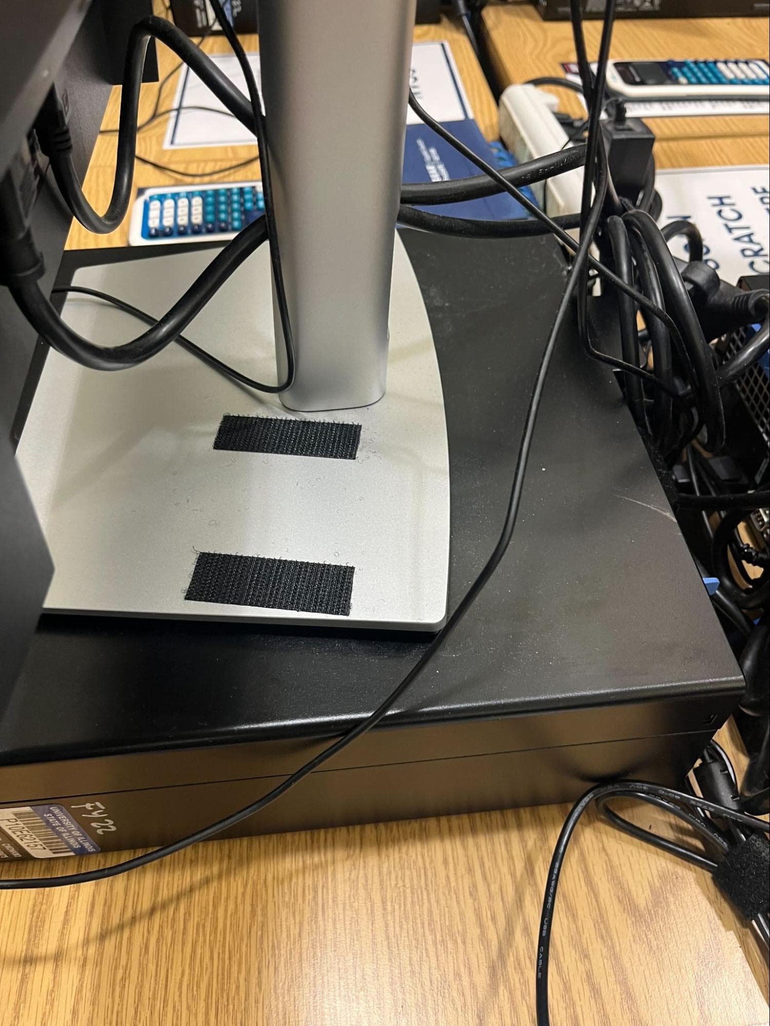 Two black Velcro strips on a monitor base, positioned front and back where the camera attaches